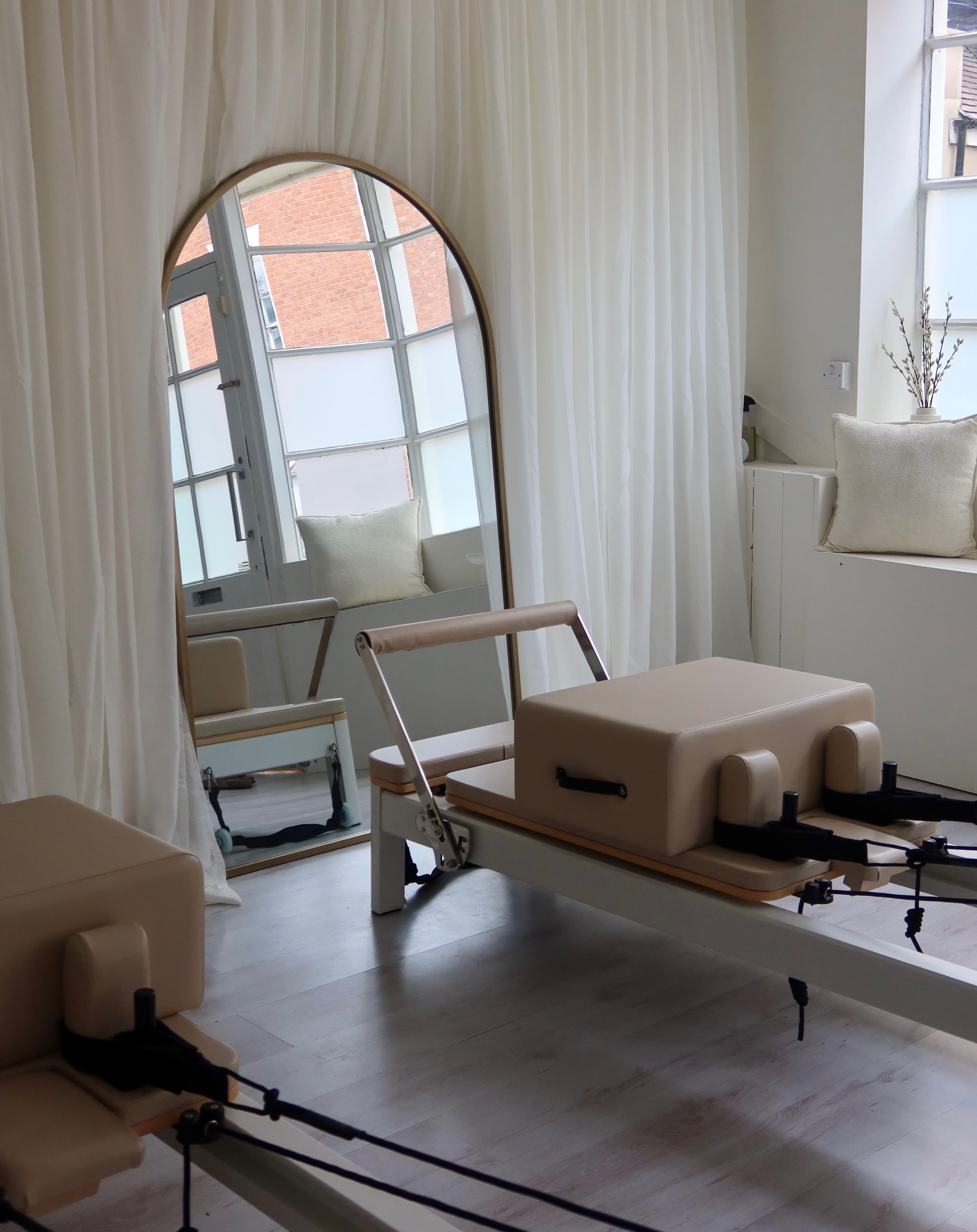 Reformer bed with arched mirror and sheer curtains